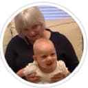 A grandma who owns a Havanese puppy holding her granddaughter